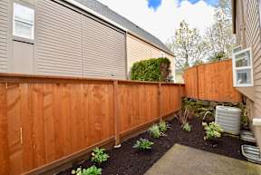 A brown wooden fence with a grey roof and a green plant in the middle.